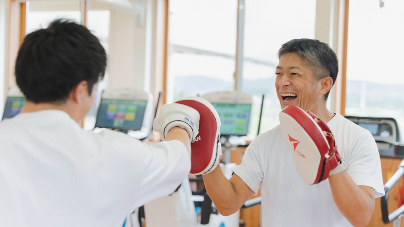 トレーニング用ミットを使う男性とサポートする男性