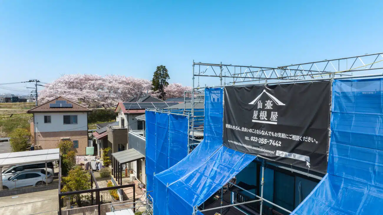 工事現場に設置された足場と菊地板金工業の看板
